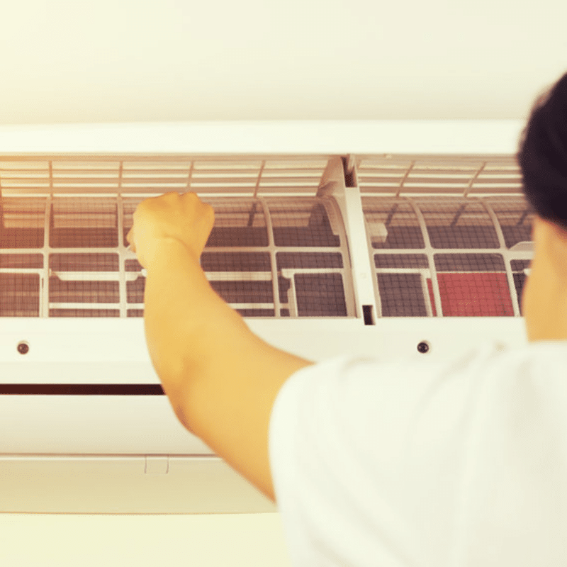 a professional ac technician adjusting the front of a ductless ac unit