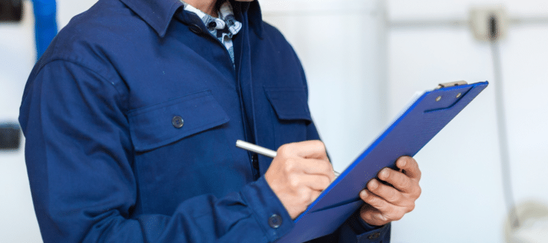 an ac service technician writing information down on a blue clipboard