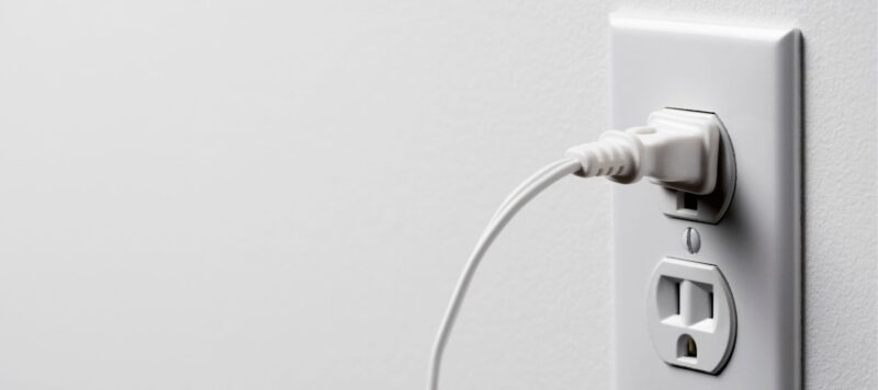 a white electrical cord plugged into an outlet on a white wall