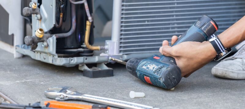 man holding a drill during an ac unit repair