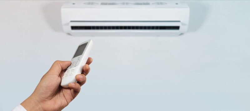 a hand using a remote to control an interior ductless AC unit