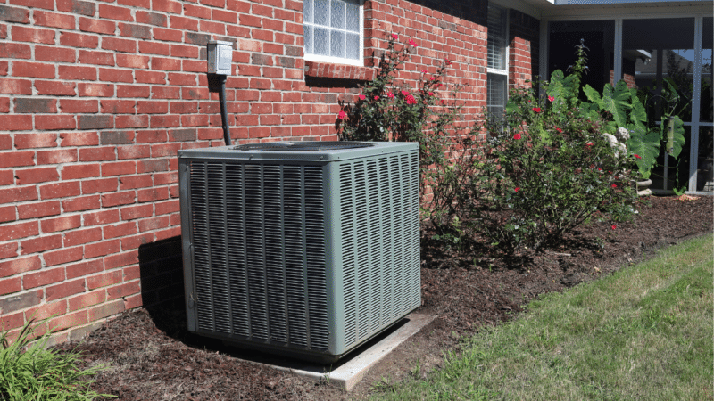 An outdoor HVAC unit outside of a red brick home.